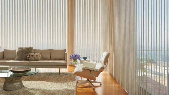 Vertical sheer panels open in living room with chair and sofa and open view