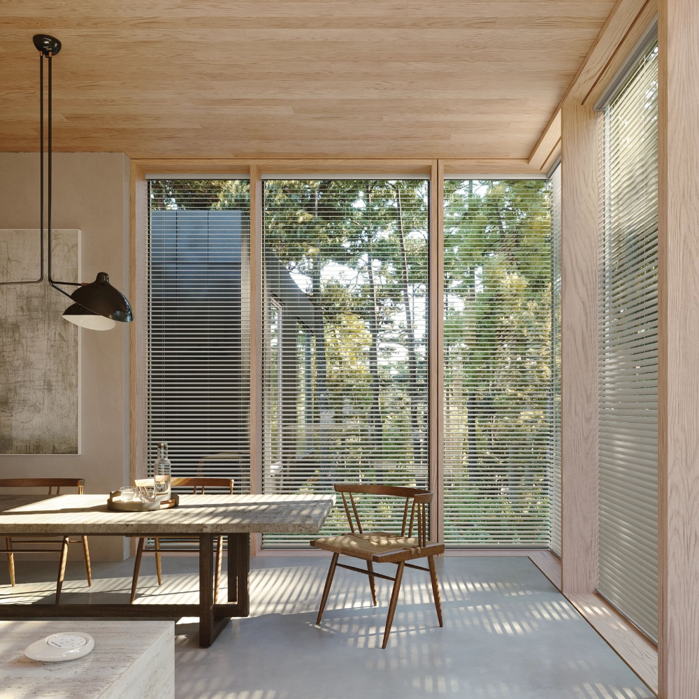 Metal blinds open on tall windows in the kitchen with a view to trees