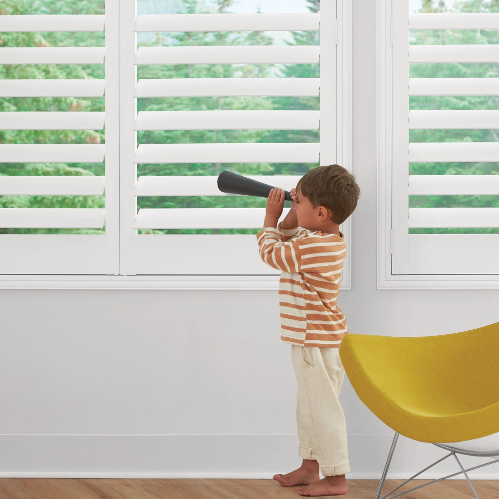 White composite shutters open with a boy using toy spyglass out the window