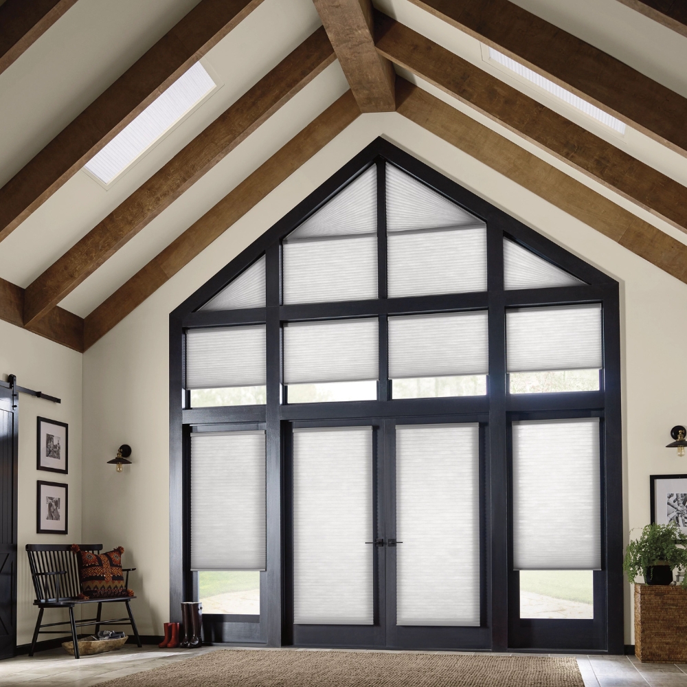 Applause Honeycomb Shades in living room covering arch windows and french door with sidelights and a row of windows above door partially open