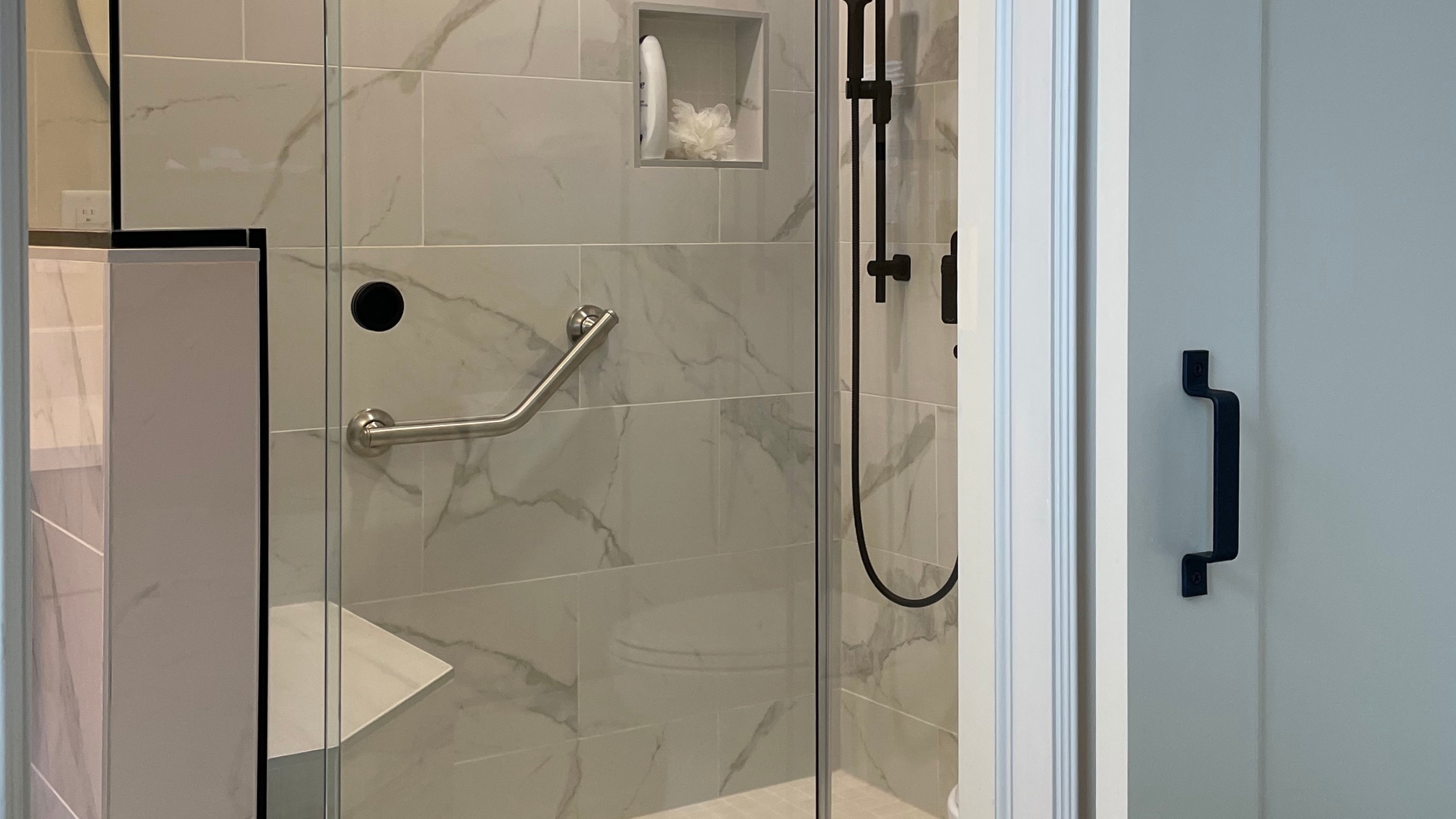 Bathroom shower with seat and glass enclosure with sliding door