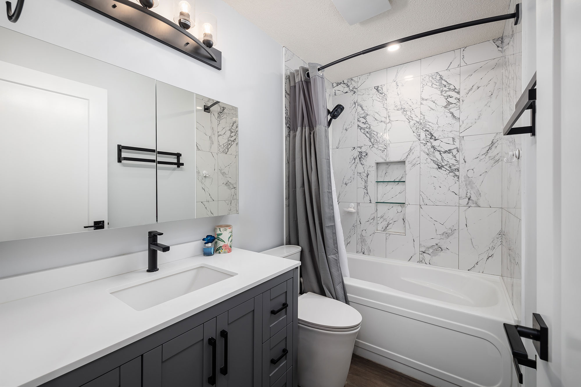 shower and tub with pot lighting, marble tile and bathroom sink