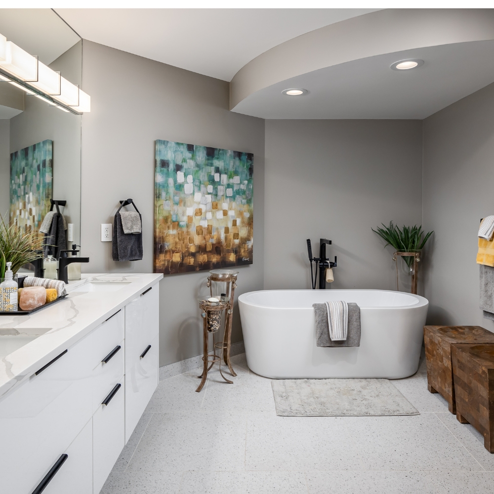 soaker tub beneath a lighting feature and dual sinks