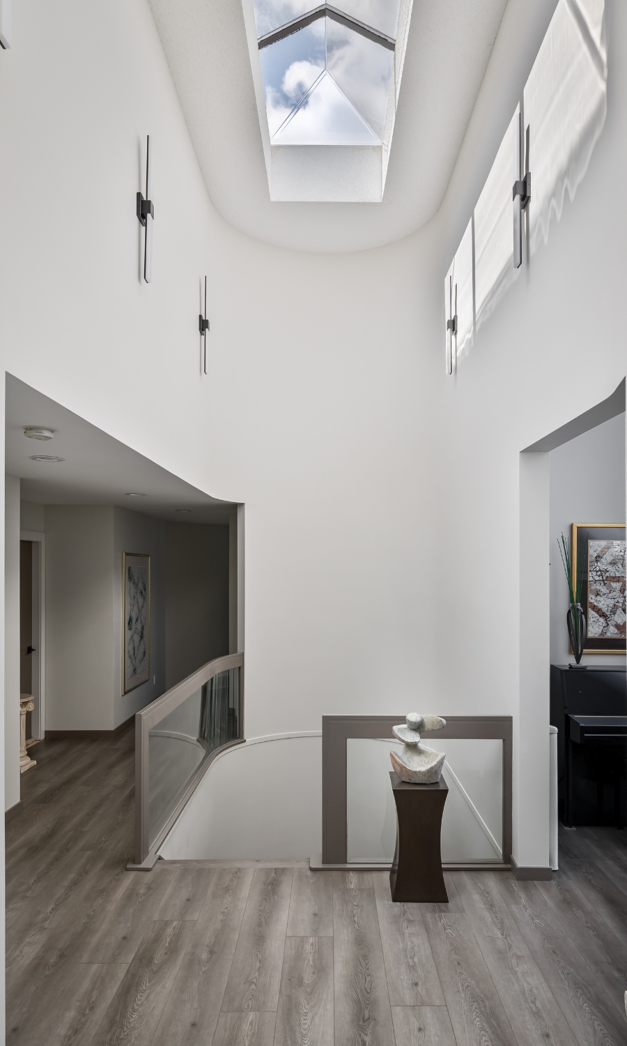 hallway with skylight and lighting sconces